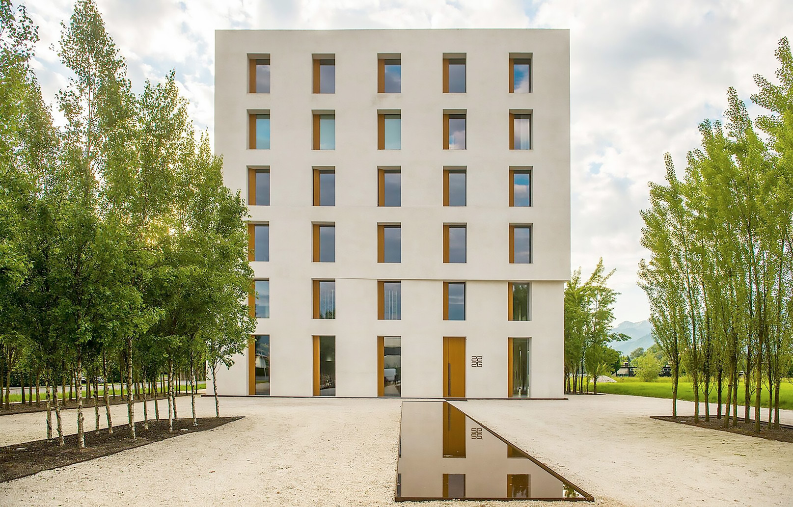 Weißer Wohnkomplex zwischen grünen Bäumen